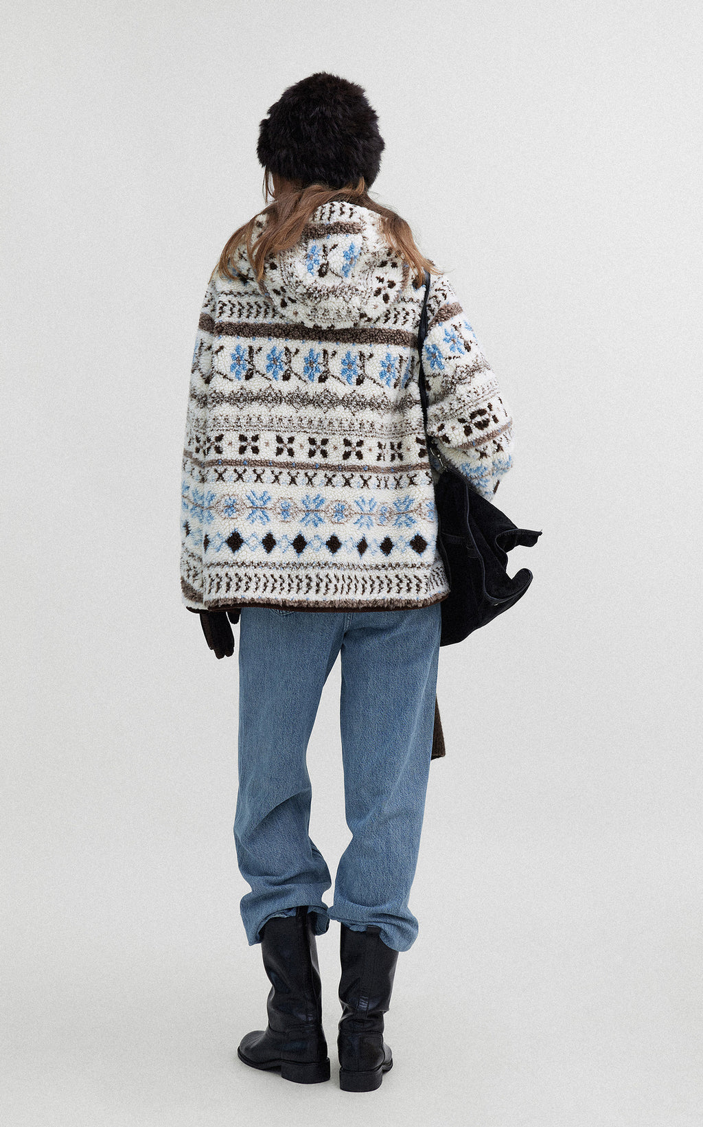 Back view of a woman wearing a Hooded Winter Jacquard Jacket with a geometric pattern and casual jeans