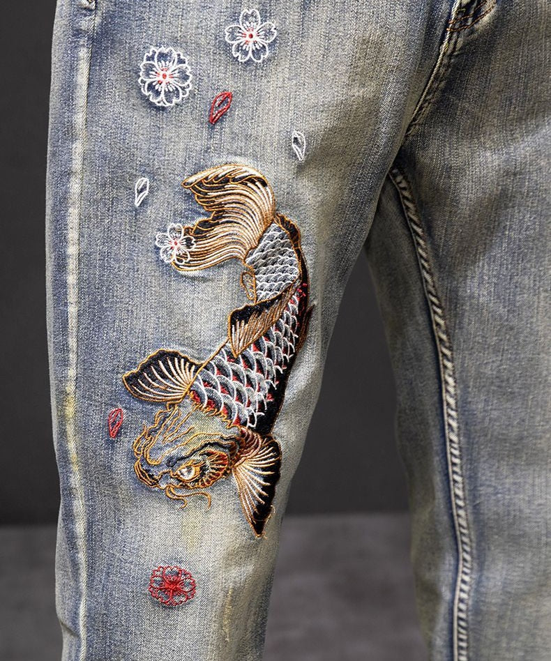 Koi Dynasty Embroidered Jeans featuring intricate koi fish and floral designs on a distressed denim fabric