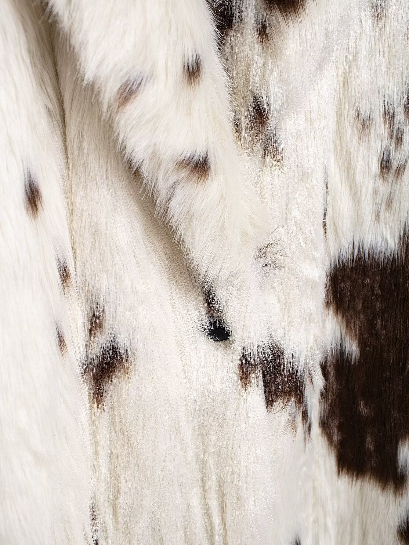Close-up of the fabric texture of a Long Faux Fur Effect Coat with a cow print design