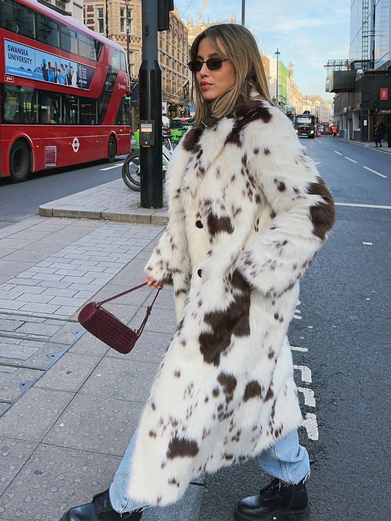 Chic woman wearing Long Faux Fur Effect Coat with spotted pattern, paired with jeans and stylish accessories