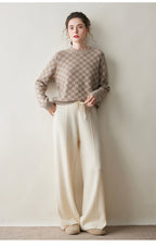 Luxury women's knit sweater in beige with a checkerboard pattern, styled with soft wide-leg pants