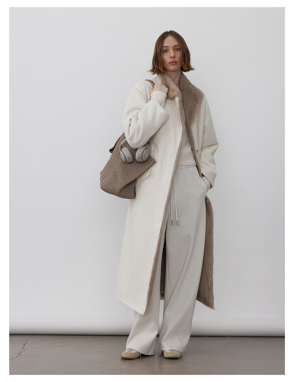 Model wearing a Milk Tea Reversible Luxe Fur Trench over white outfit, showcasing its stylish design