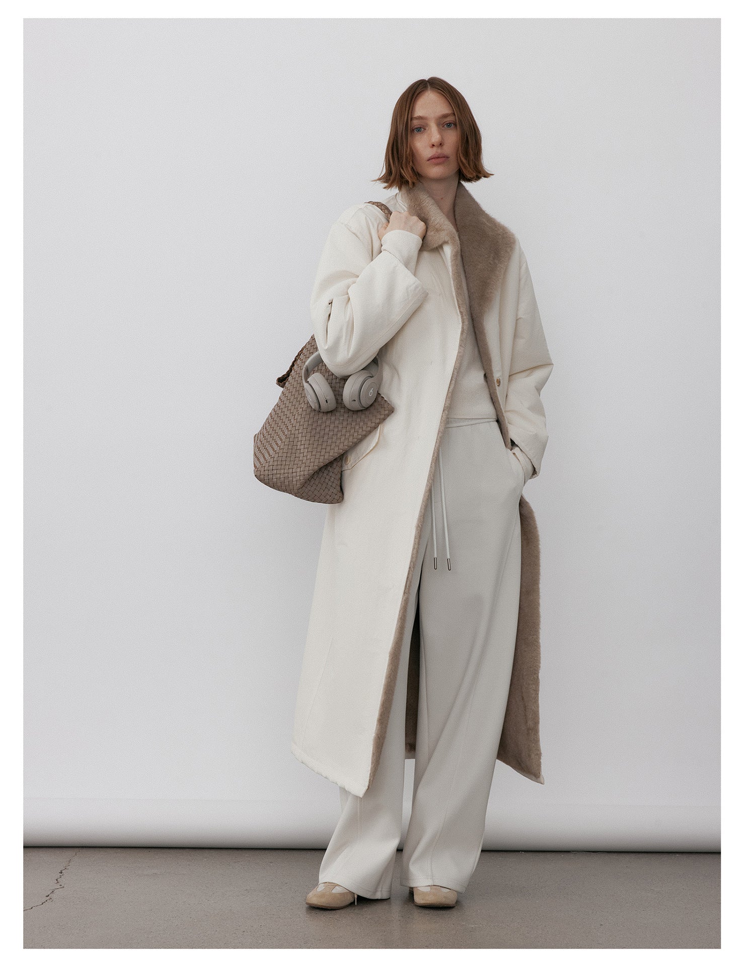 Model wearing a Milk Tea Reversible Luxe Fur Trench over white outfit, showcasing its stylish design