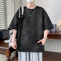 Casual black minimalist t-shirt for men with a loose fit, styled with gray shorts and accessories