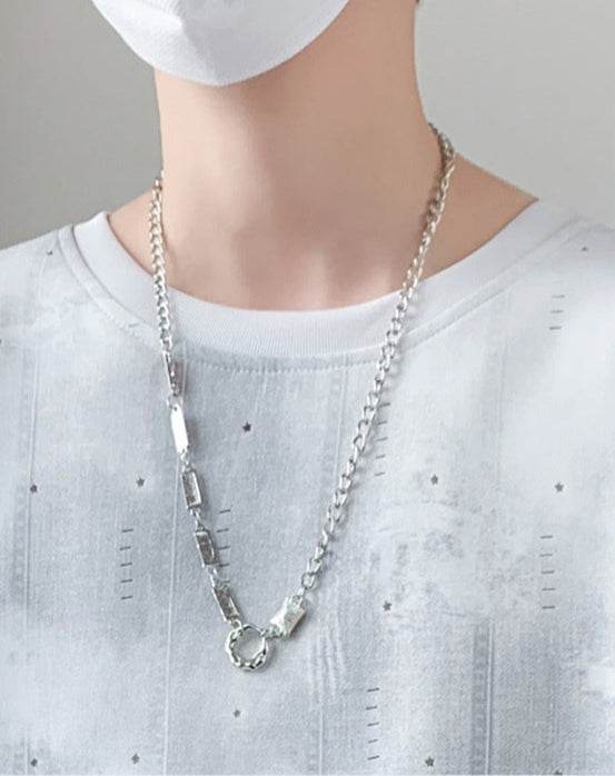 Minimalist t-shirt for men worn with a silver chain necklace, featuring a modern design