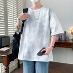 Men wearing a stylish minimalist t-shirt for men in a casual setting with a phone in hand