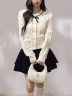 Fashionable model wearing Moonlight Ribbon Cardigan with a black skirt and a stylish handbag