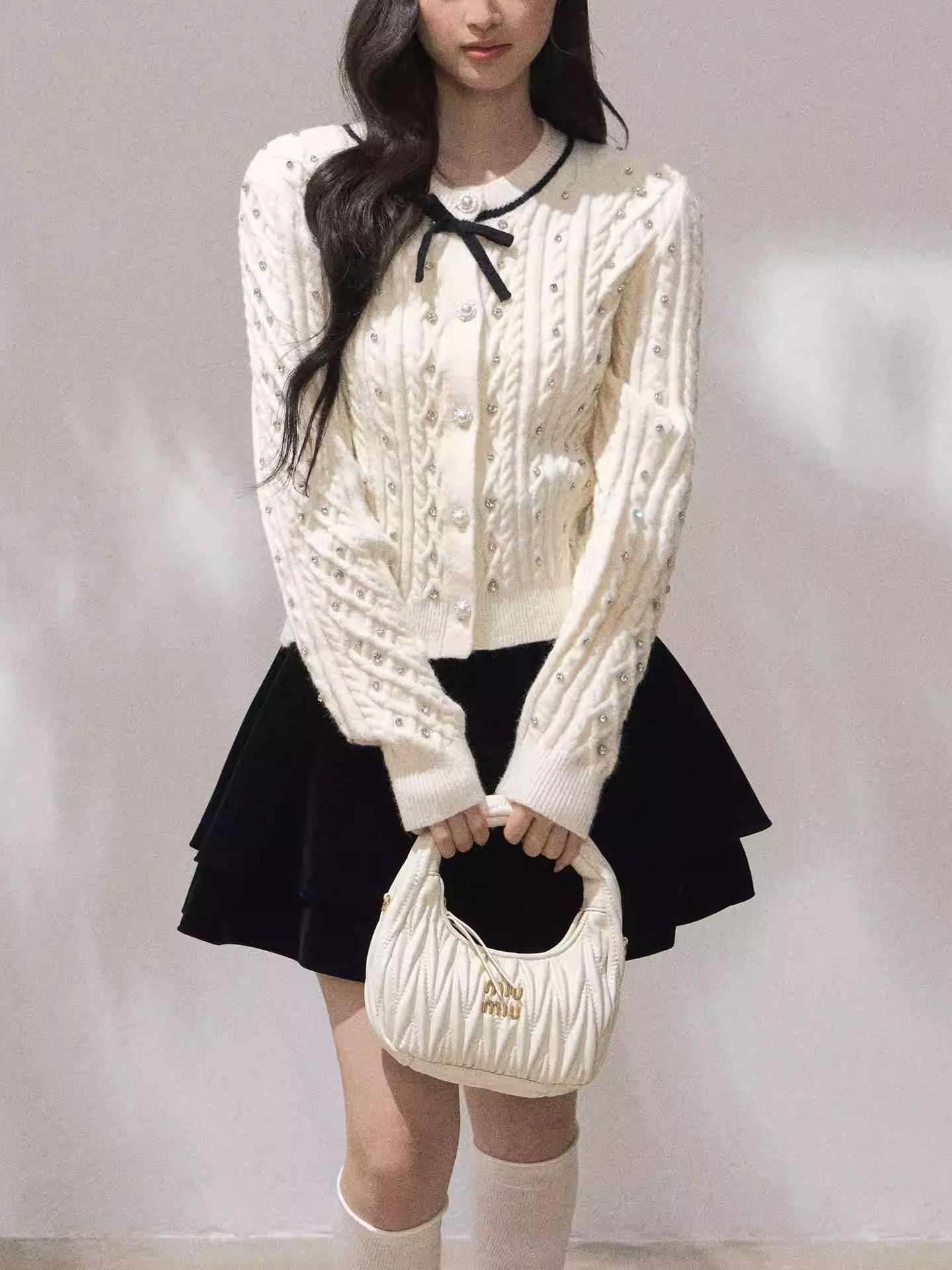 Fashionable model wearing Moonlight Ribbon Cardigan with a black skirt and a stylish handbag