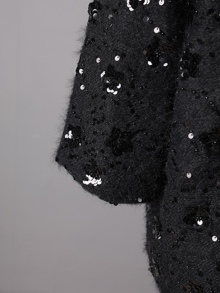 Close-up of the sleeve of an Oversize Jacket with Applications featuring black sequins and a textured fabric