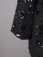 Close-up of the sleeve of an Oversize Jacket with Applications featuring black sequins and a textured fabric