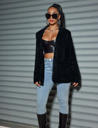 Stylish model wearing an oversized sequin cardigan blazer over a black top and light jeans