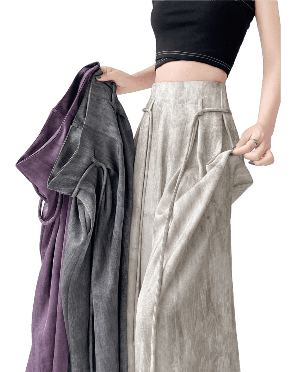Femeie purtând pantaloni casual wide-leg bej și ținând alte pantaloni casual wide-leg în nuanțe de gri și violet