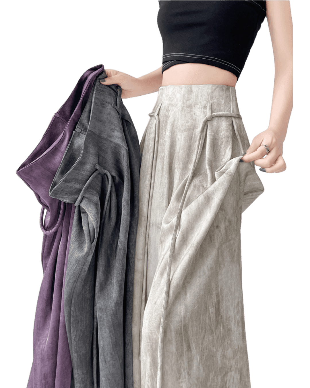 Femeie purtând pantaloni casual wide-leg bej și ținând alte pantaloni casual wide-leg în nuanțe de gri și violet