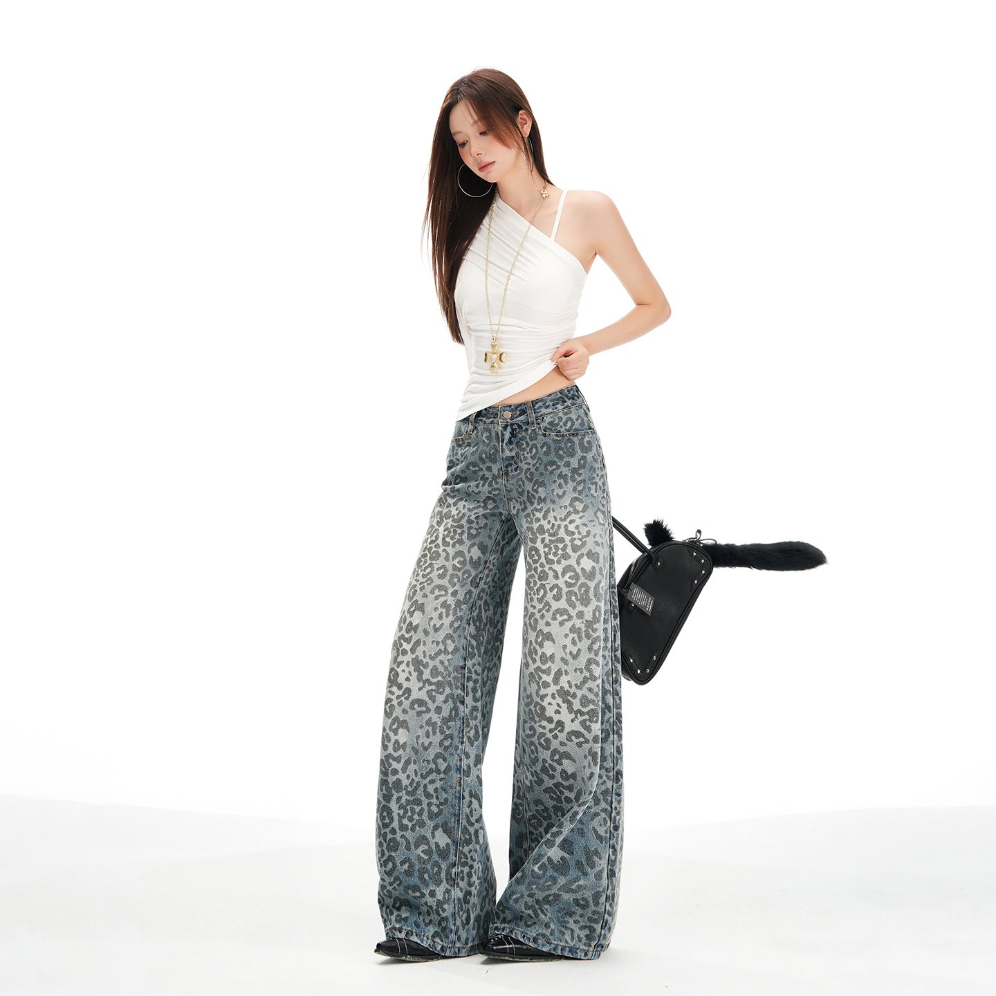 Pantaloni largi din denim cu imprimeu leopard, stil modern, purtați cu tricou alb și accesorii elegante.