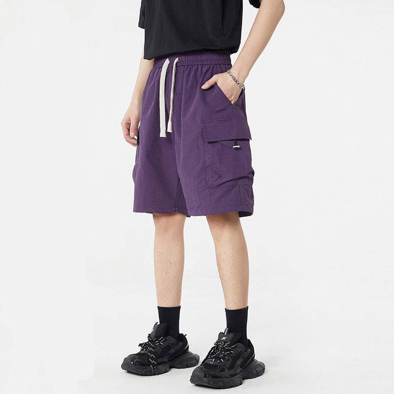 Pantaloni scurți casual cu buzunare multiple de culoare mov purtați cu tricou negru și adidași negri
