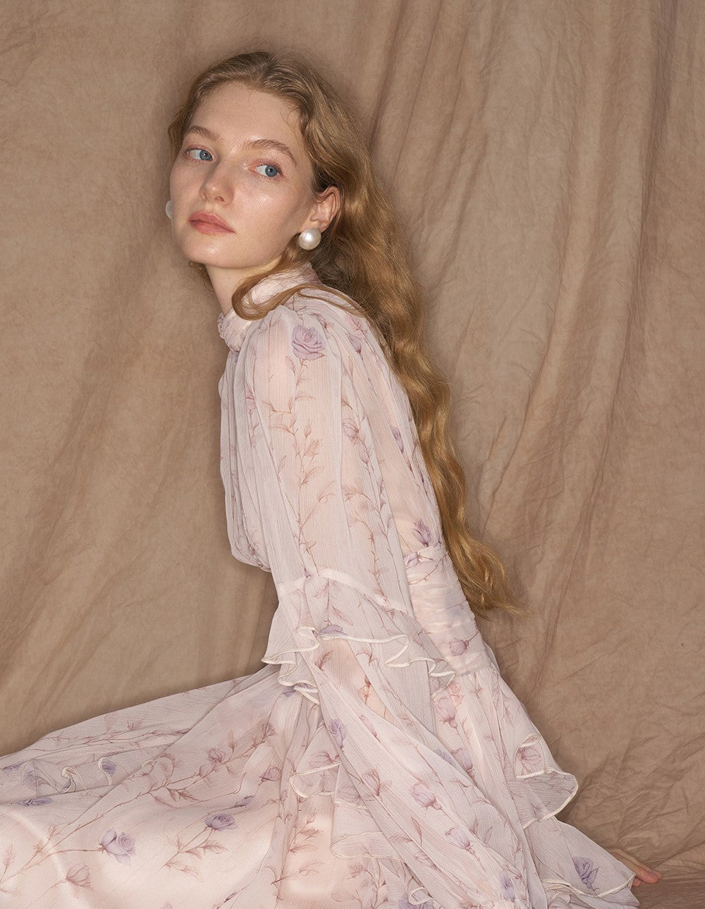 Model wearing Provence Bloom Midi Dress in soft floral design with ruffled sleeves and elegant details