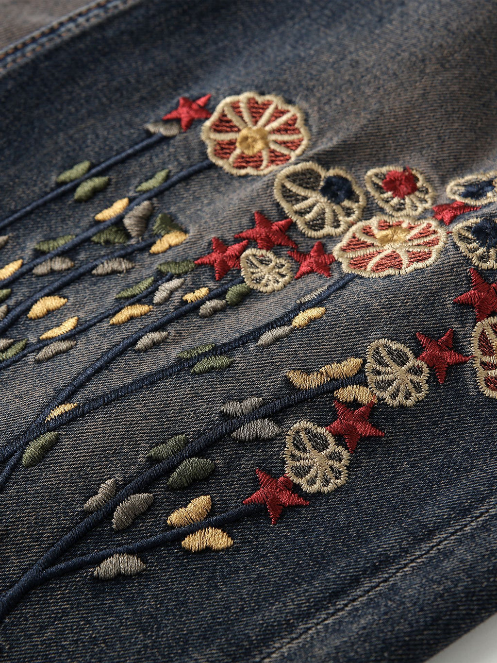 Close-up of RetroBloom Embroidered Jeans showcasing colorful floral designs on dark denim