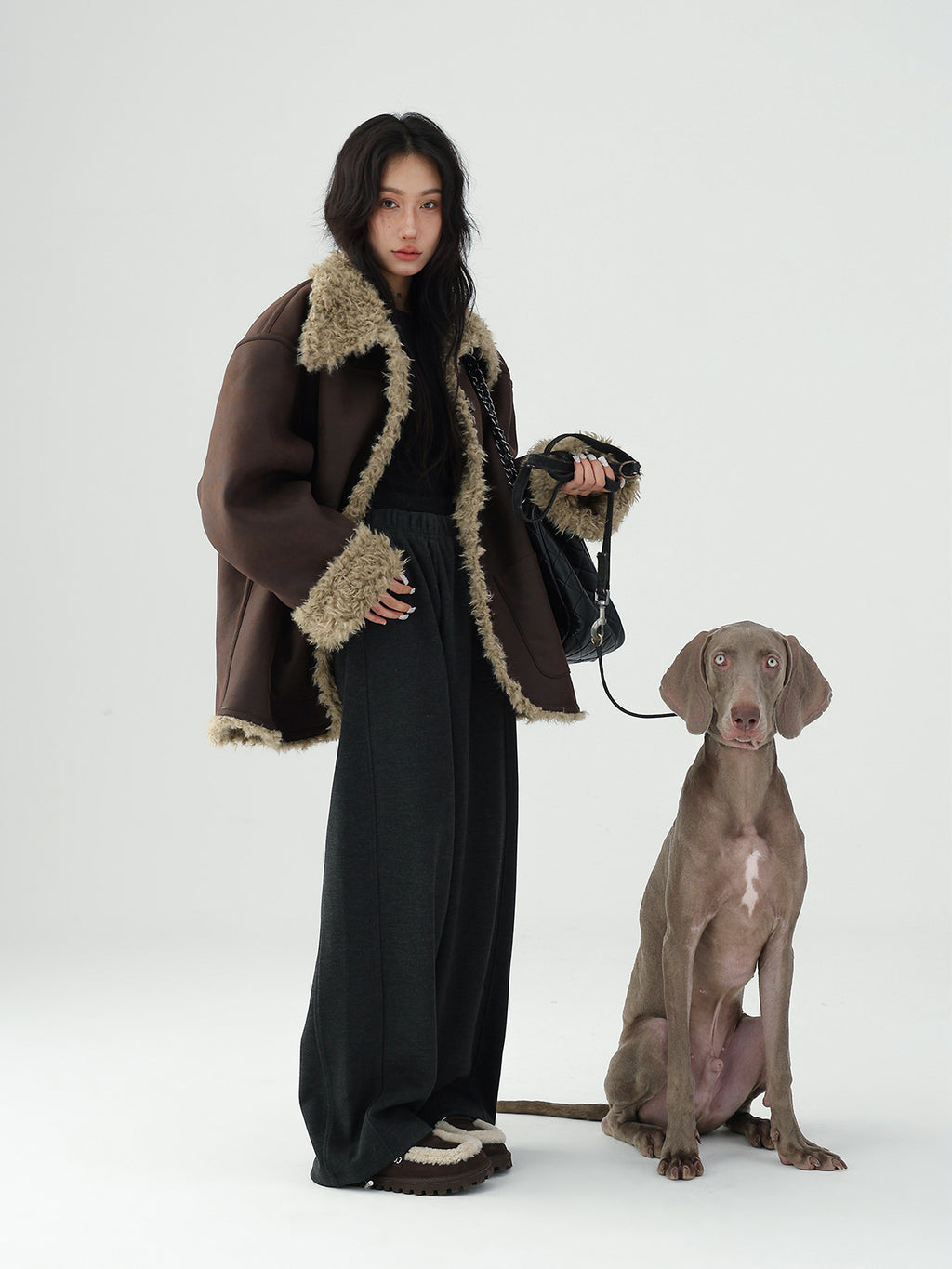 Model in a Reversible Winter Suede Jacket styled with wide-leg pants next to a dog