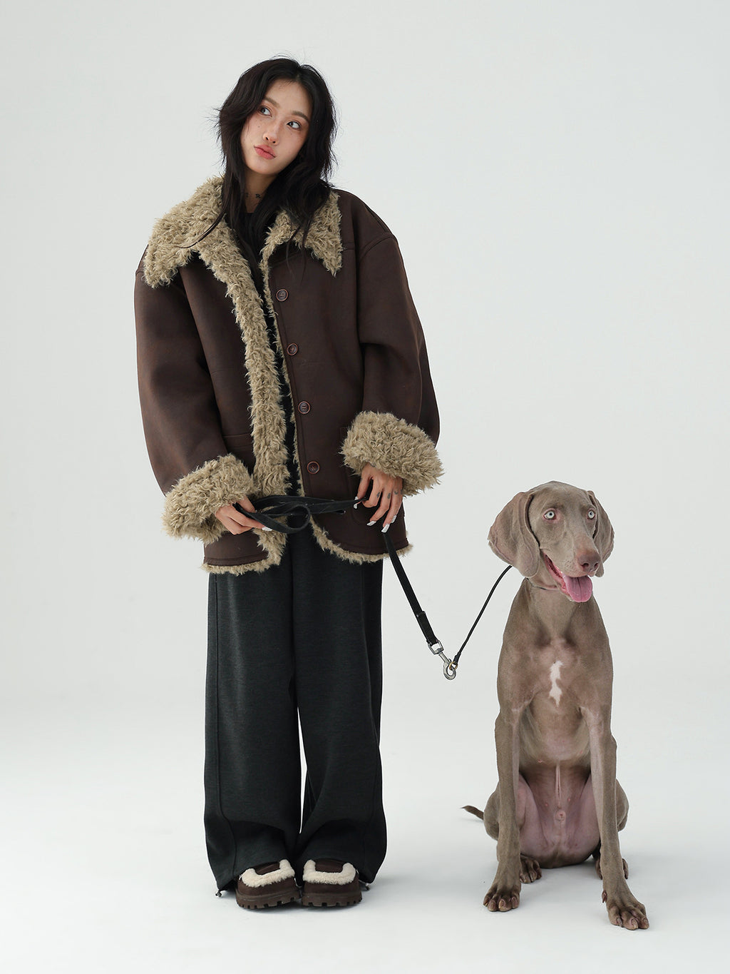 Model wearing a Reversible Winter Suede Jacket with fur trim alongside a dog in a neutral setting