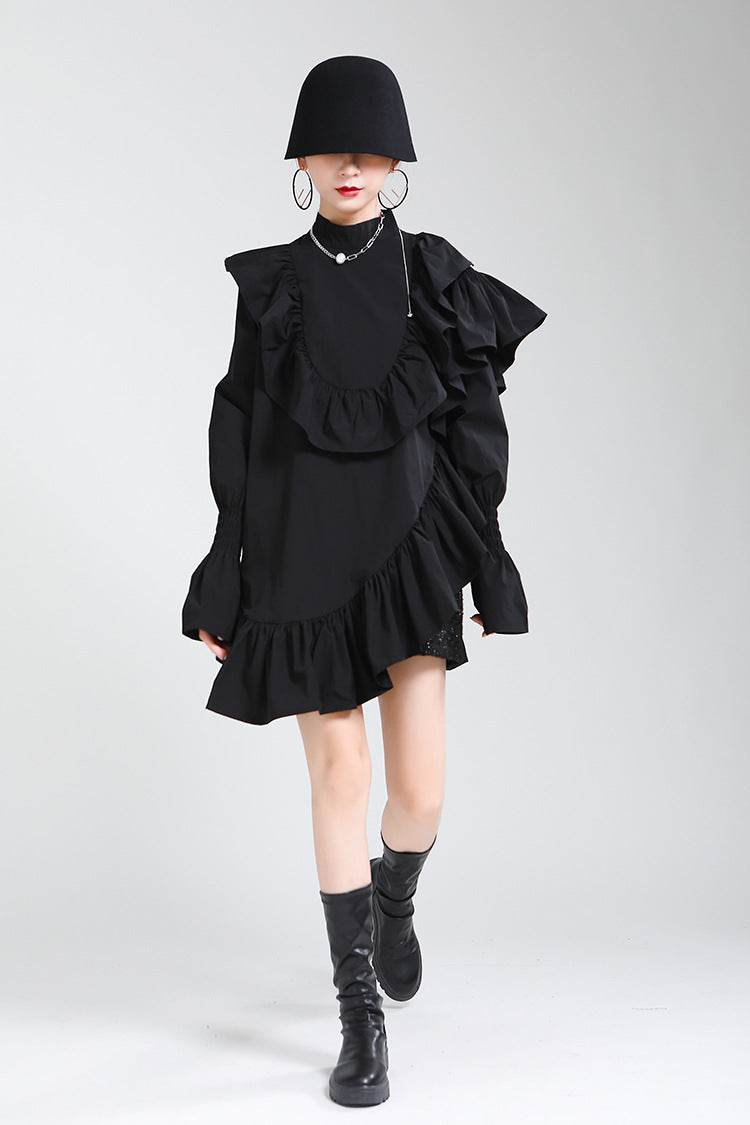 Rochie asimetrică cu volane neagră purtată de femeie cu pălărie și cizme negre