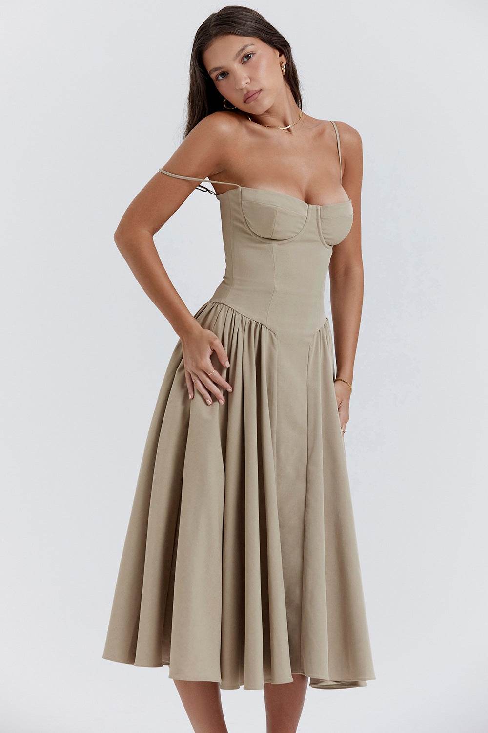 Femeie purtând o rochie cu design minimalist bej, cu bretele subțiri și fustă evazată midi
