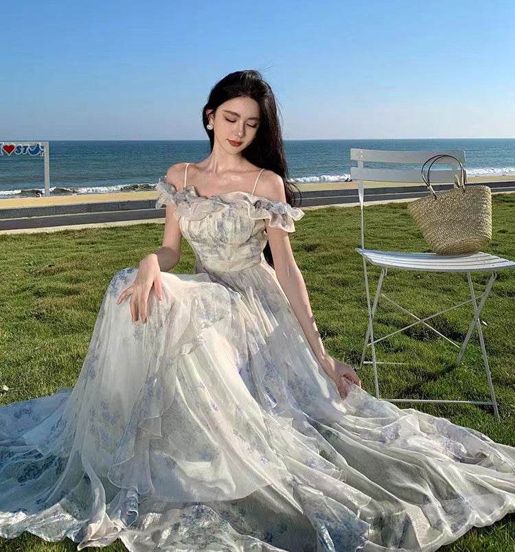 Rochie vaporoasă cu volane purtată de femeie pe iarbă lângă mare într-o zi senină