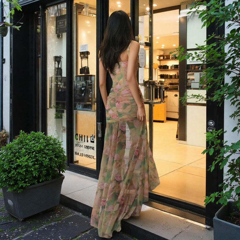 Femeie purtând o rochie elegantă de vară cu imprimeu floral, în fața unei cafenele