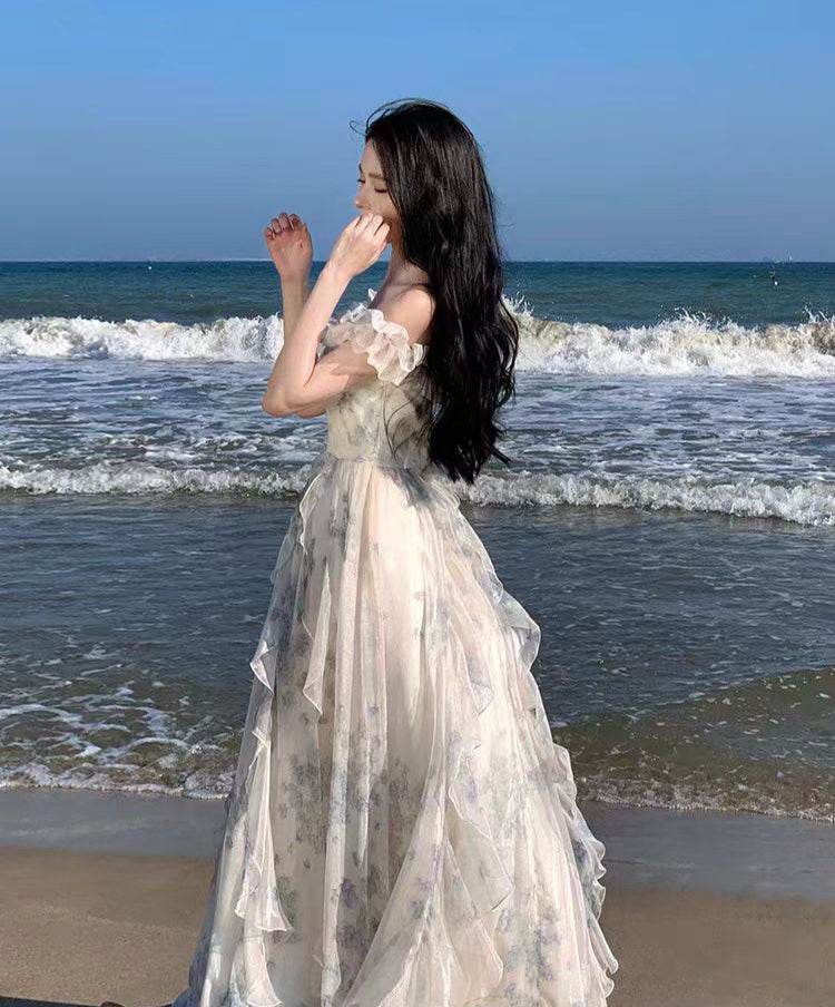 Rochie lungă vaporoasă cu volane și imprimeu floral purtată pe plajă în fața mării