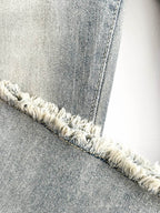 Close-up of Stretch flared jeans with frayed hem detail showcasing a light wash denim texture