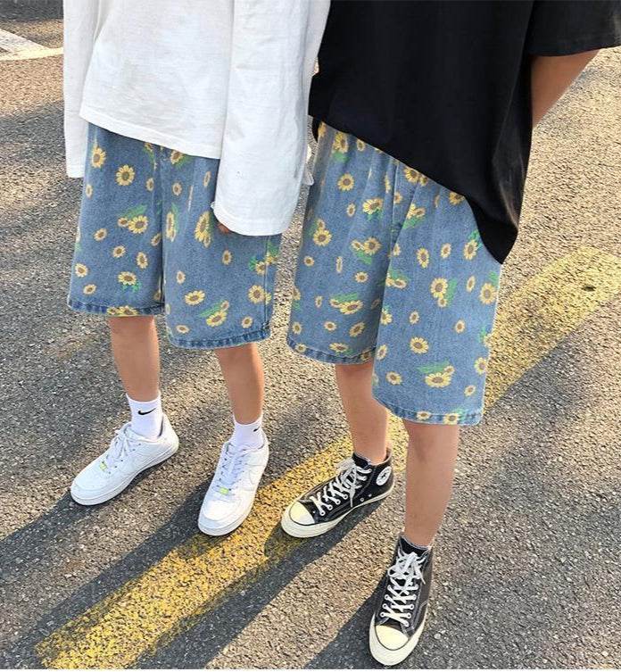 Two individuals wearing summer streetwear floral shorts with a sunflower print and casual sneakers