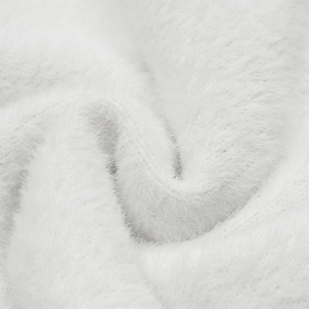 Close-up of soft white fabric texture for the Sweet Bear Knit Sweater, showcasing its cozy material