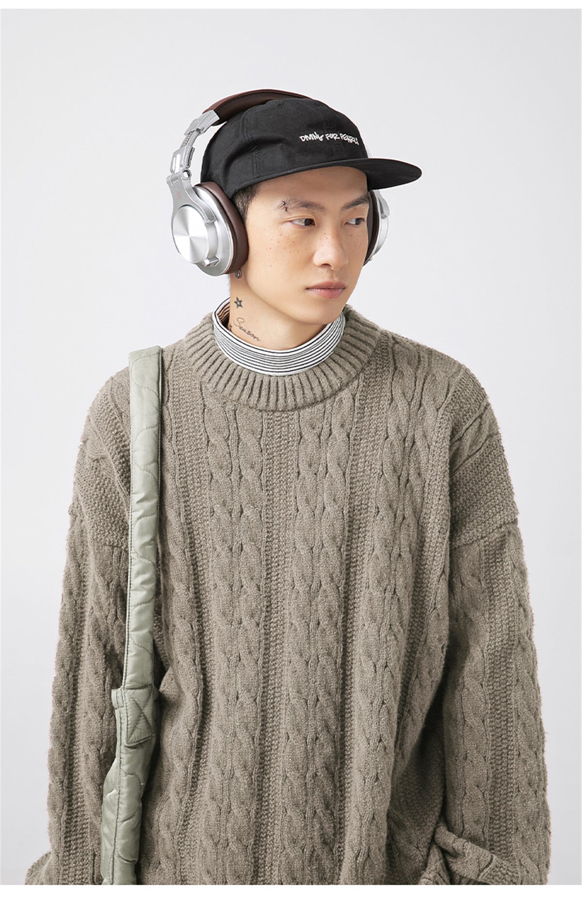 Model wearing a stylish Textured Cable Knit Sweater in brown with headphones and a cap