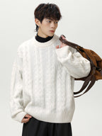 Men's textured cable knit sweater in white, styled with casual black pants and a brown bag