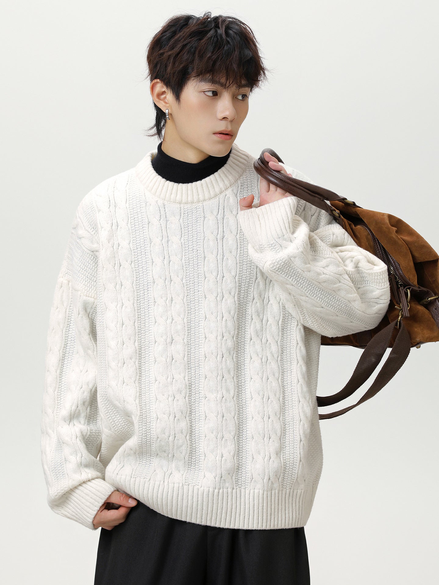 Men's textured cable knit sweater in white, styled with casual black pants and a brown bag