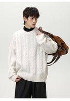 Model wearing a white textured cable knit sweater paired with black pants and a brown shoulder bag