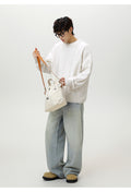 Model wearing a cozy Textured Cable Knit Sweater in white with relaxed fit jeans and a handbag