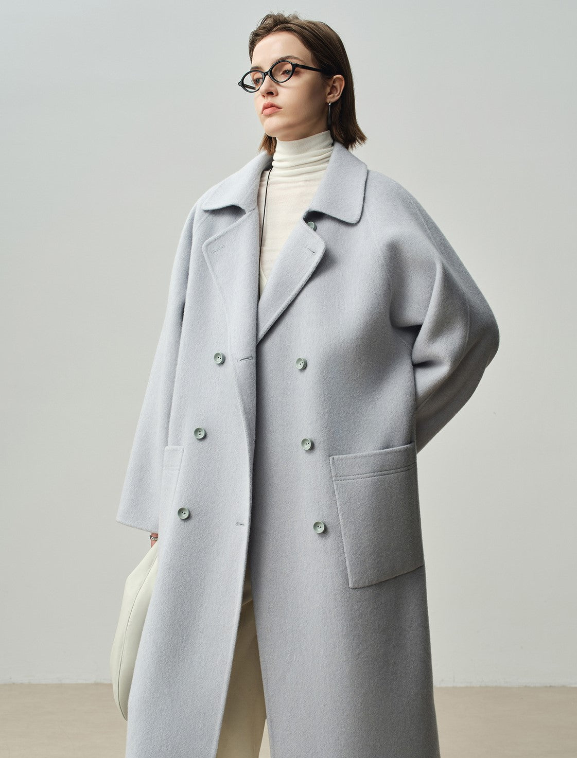 The Amaya Pastel Coat in light gray featuring a relaxed fit and large front pockets