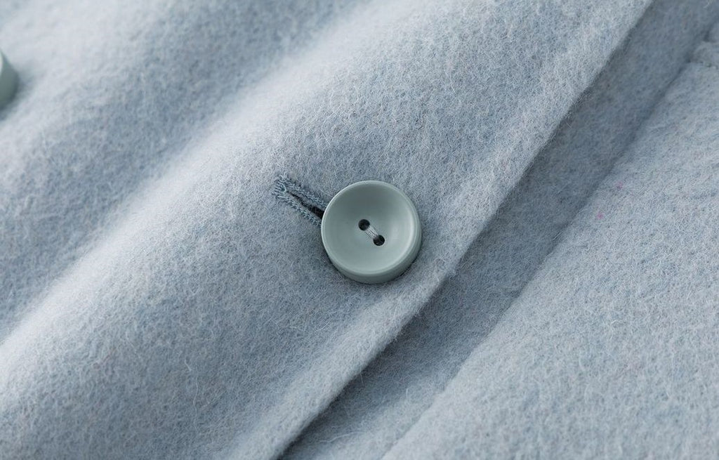 Close-up of a button detail on The Amaya Pastel Coat in soft blue fabric for a stylish look