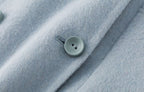 Close-up of a button detail on The Amaya Pastel Coat in soft blue fabric for a stylish look