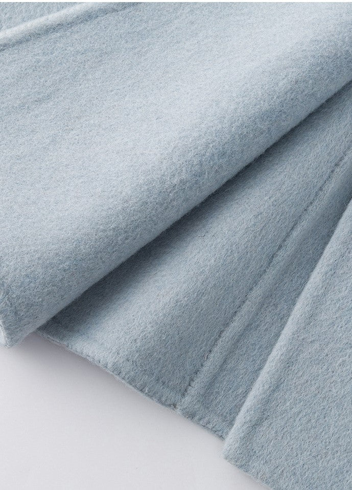 The Amaya Pastel Coat in soft blue fabric with a smooth texture and elegant drape