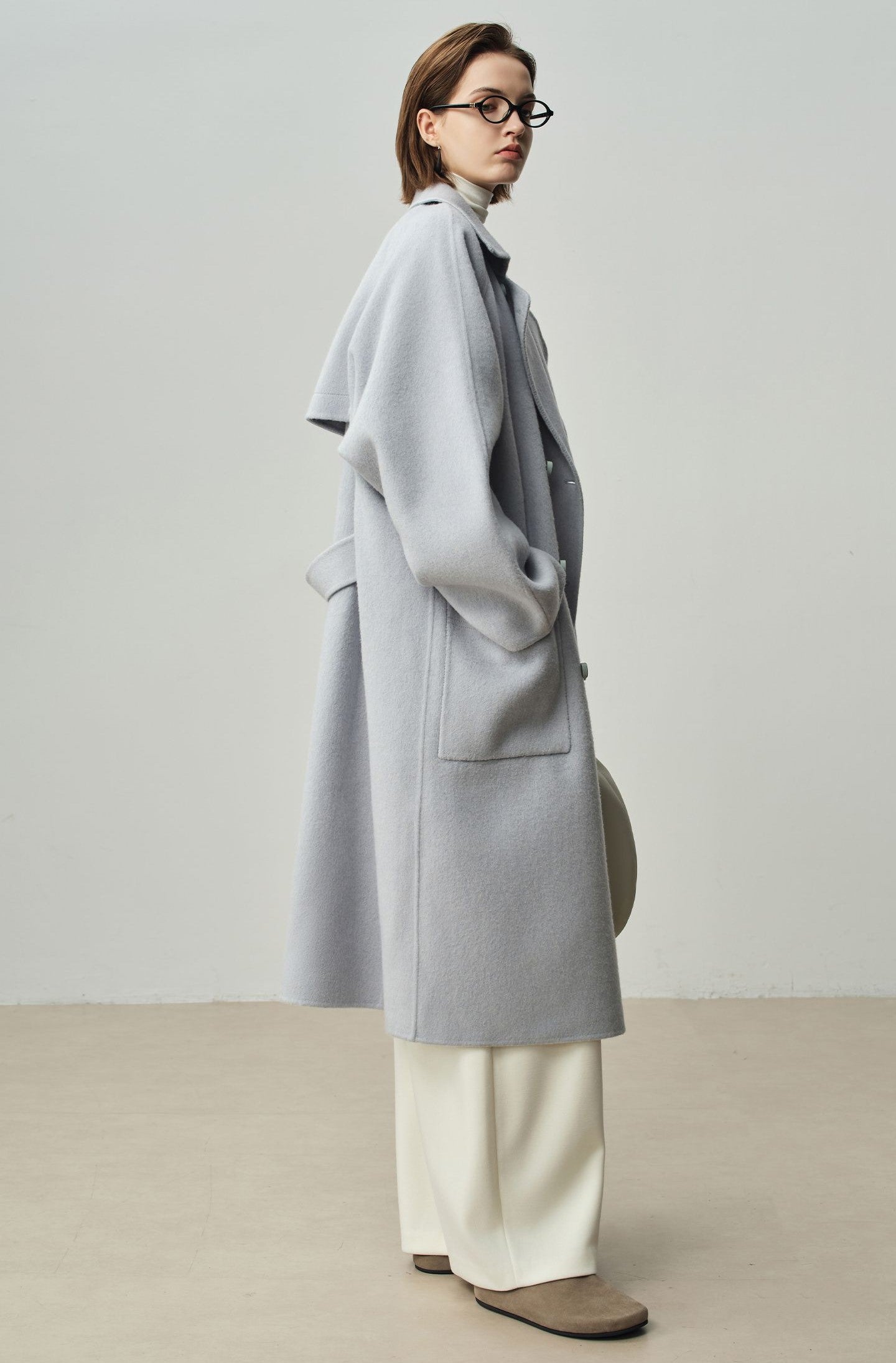The Amaya Pastel Coat in soft gray, paired with stylish wide-leg trousers for a chic look.