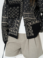 The Kyoto Jacquard Cardigan with intricate patterns, paired with beige shorts for a stylish look