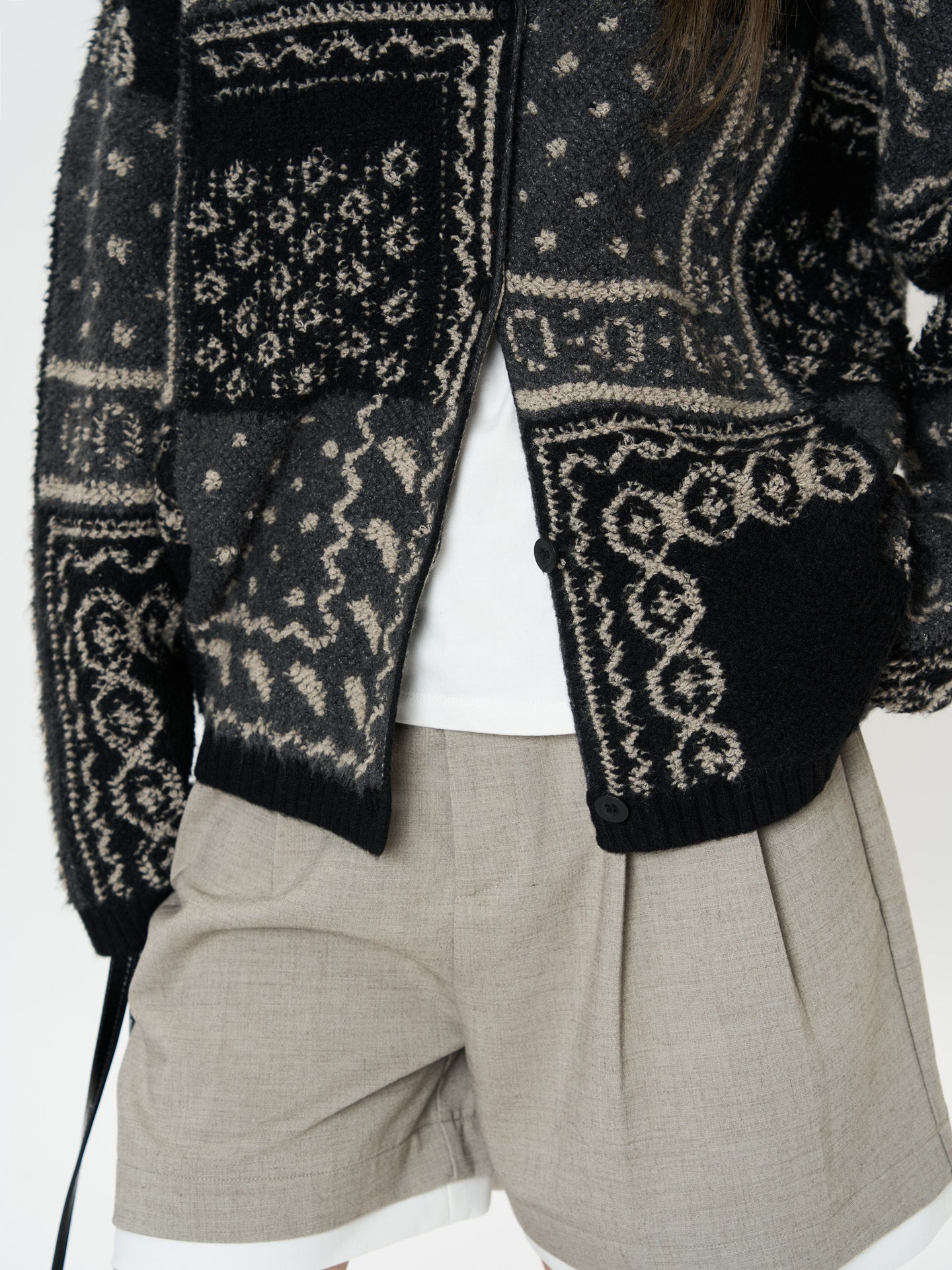 The Kyoto Jacquard Cardigan with intricate patterns, paired with beige shorts for a stylish look