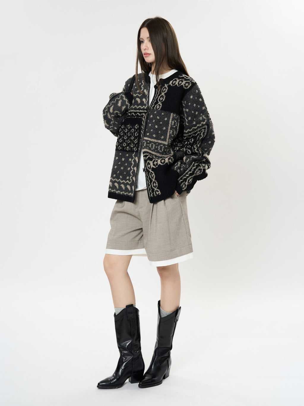 The Kyoto Jacquard Cardigan in black with intricate patterns, styled with shorts and boots