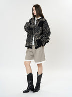The Kyoto Jacquard Cardigan in black with intricate patterns, styled with shorts and boots