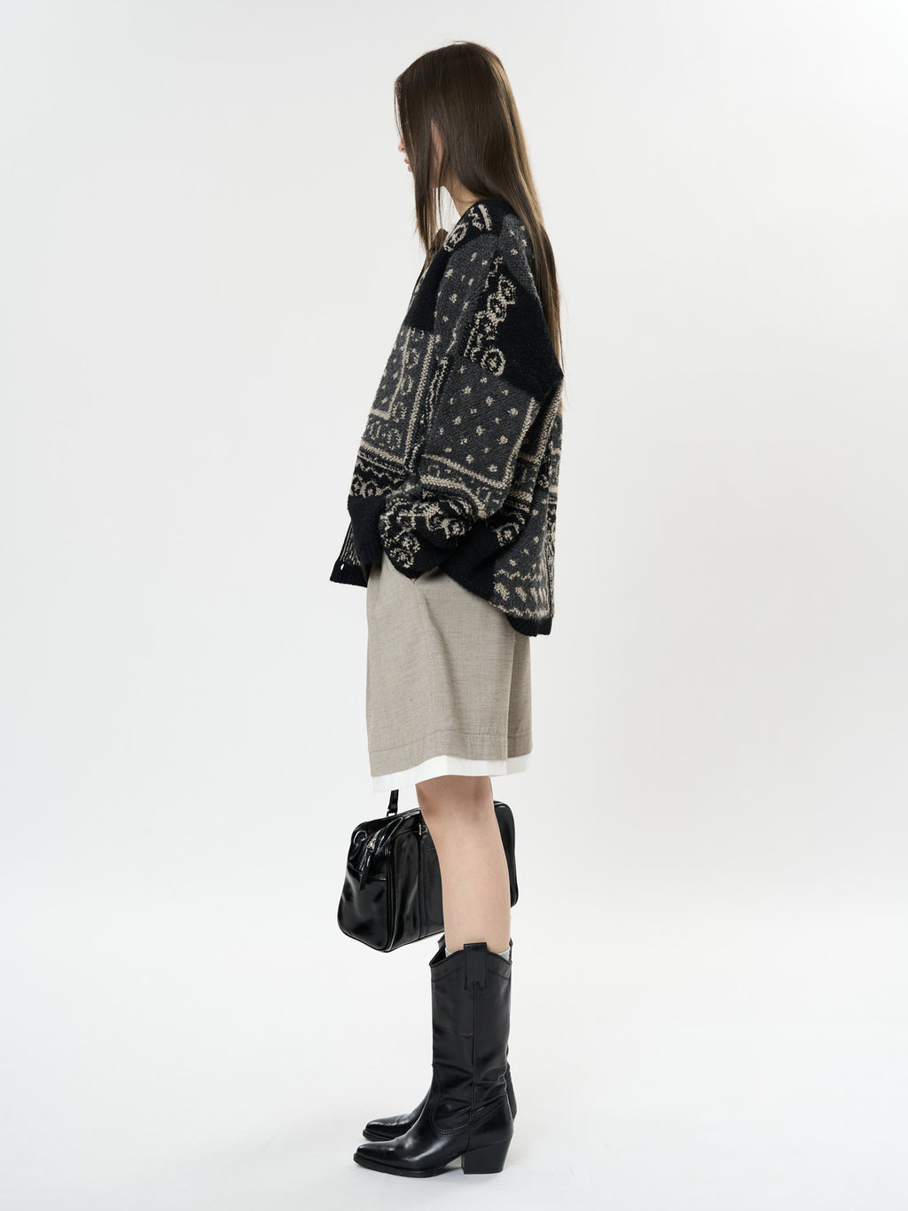 Side view of a model wearing The Kyoto Jacquard Cardigan paired with a beige skirt and black knee-high boots