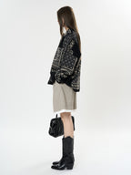 Side view of a model wearing The Kyoto Jacquard Cardigan paired with a beige skirt and black knee-high boots