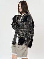 The Kyoto Jacquard Cardigan in black and gray patterns, stylishly worn over a shirt and shorts
