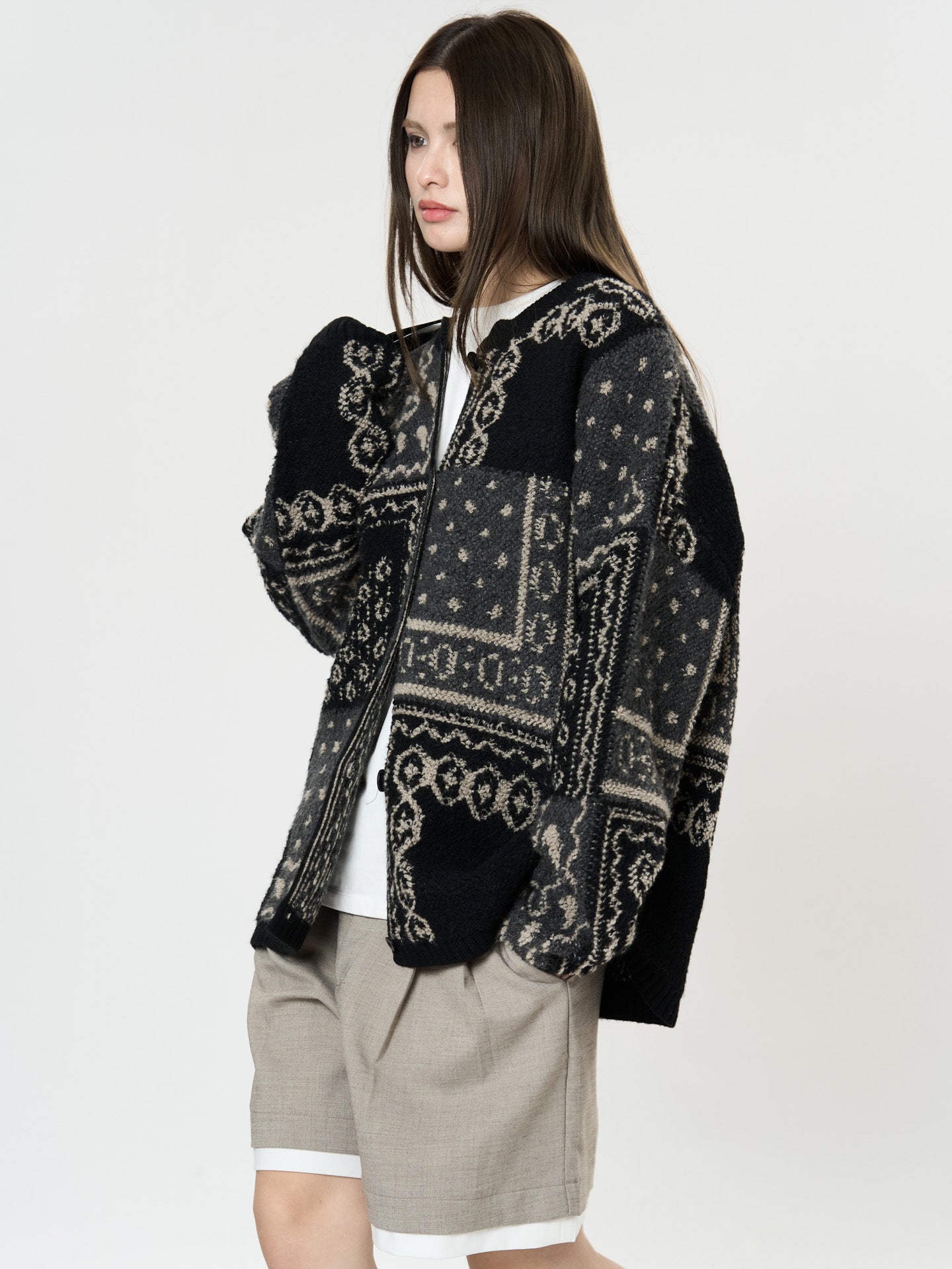 The Kyoto Jacquard Cardigan in black and gray patterns, stylishly worn over a shirt and shorts