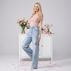 Model wearing Twin Blossom Wide Leg Jeans with floral embroidery, styled with a pink top against a floral background